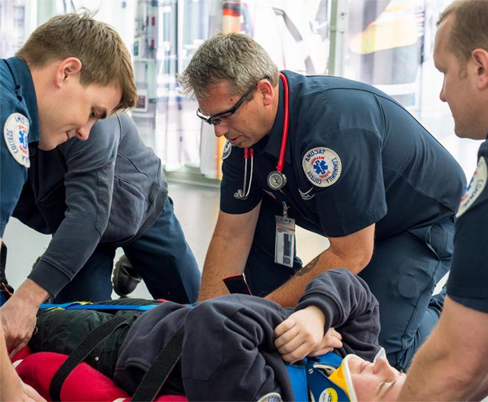 four ems students practicing backboarding